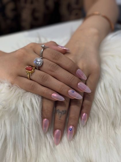 This is a beautiful example of a soft chrome look. I used a light pink iridescent chrome for a delicate, pearly shine on these long stiletto nails. I also added a tiny, hand-painted evil eye for a personal touch of protection.