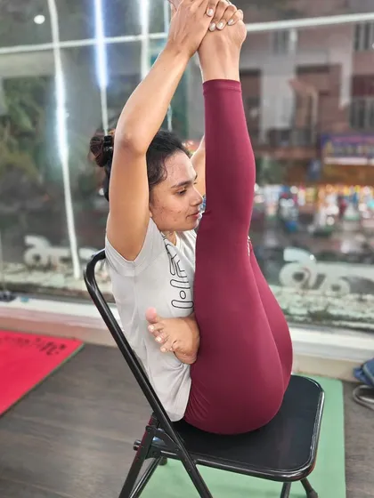 This challenging seated pose, performed on a chair, requires deep hamstring flexibility and core engagement.