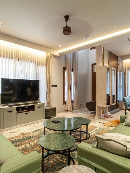 The living room of "Vertical Nest," a cozy and stylish space designed for family gatherings. The green sofa adds a pop of color, while the large windows flood the room with natural light.