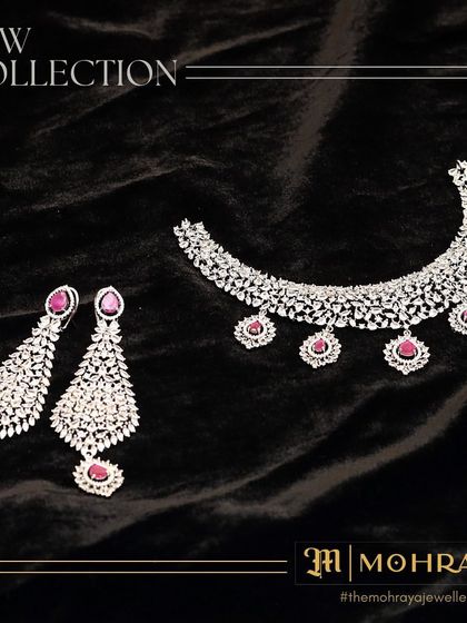 Our new collection features this stunning ruby and diamond necklace with matching chandelier earrings, laid out on a black velvet background.