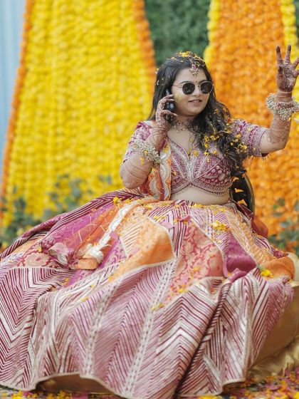 A cool bride on the phone during her Haldi. Her makeup is effortless and chic, with a subtle glow that enhances her features.