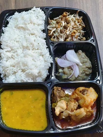 This is our Chicken Manipuri Thali, packed for delivery. It features Manipuri-style chicken curry, dal, iromba (a fermented fish and vegetable mash), a fresh salad called singju, and steamed rice.