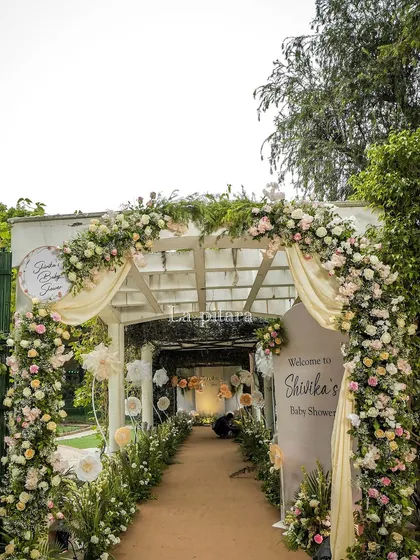 A beautiful floral archway for a 'Baby in Bloom' themed baby shower. The entrance is designed to feel soft and welcoming, using a delicate palette of pastel flowers and gentle drapery to create a serene and celebratory atmosphere for the parents-to-be.