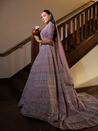 A full-length shot of the lavender lehenga on a grand staircase. The styling creates a look of pure fairytale elegance.