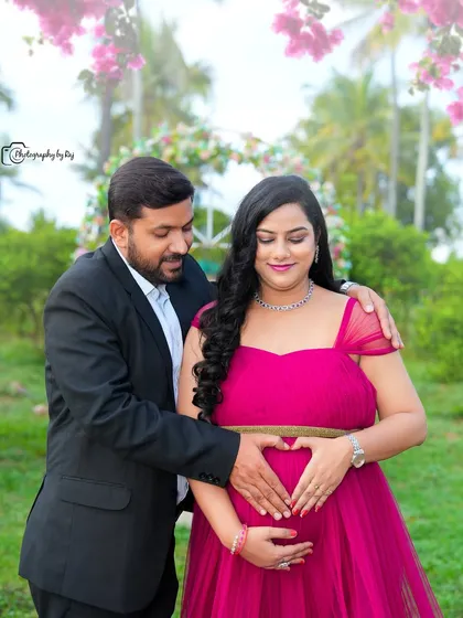 A sweet gender reveal photo with a sign announcing "It's a girl!". The couple is framed by a floral arch.