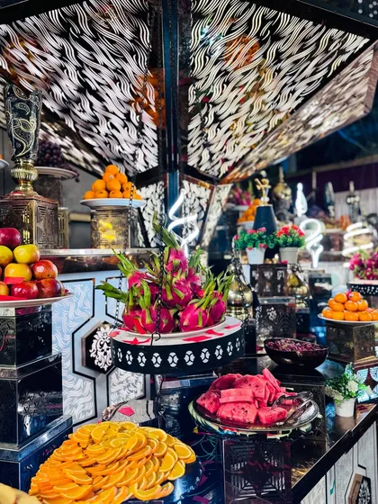 An elaborate and artistic fresh fruit display. I use a variety of local and exotic fruits like dragon fruit, sliced oranges, and apples, presented on a multi-tiered, modern counter to create a visual feast.
