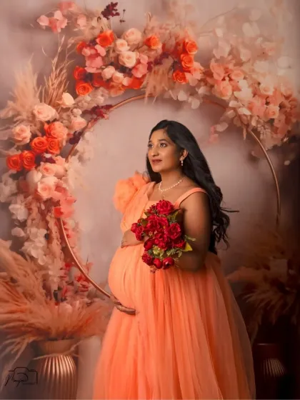 Holding a bouquet of red roses, this mama-to-be looks radiant and full of life. The contrast of the red against the peach and cream florals is stunning.
