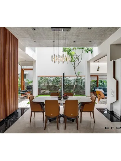 The dining area in the 'Floating Walls' project, situated within a double-height space and flanked by a central courtyard. The design ensures the home is filled with light and has a constant connection to nature.