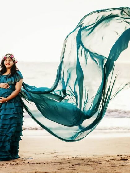 A beachside maternity shoot is the perfect setting for this flowing teal gown. The dress features a long trail that catches the ocean breeze, adding beautiful movement and a touch of drama to your photos.