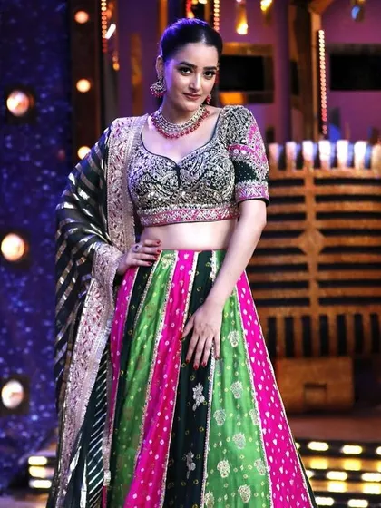 This vibrant multi-panel lehenga in shades of green and pink is a true showstopper. The detailed blouse and striped dupatta create a unique and festive look.