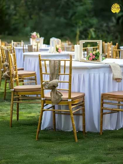 The details matter. This close-up shows the elegant table setting with rustic burlap ties on chiavari chairs, perfect for a chic, garden-themed wedding reception.