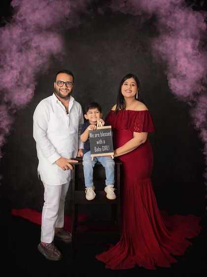A dramatic and beautiful gender reveal. We used colored smoke to announce the arrival of a baby girl, creating a stunning visual against the rich red gown and dark backdrop.