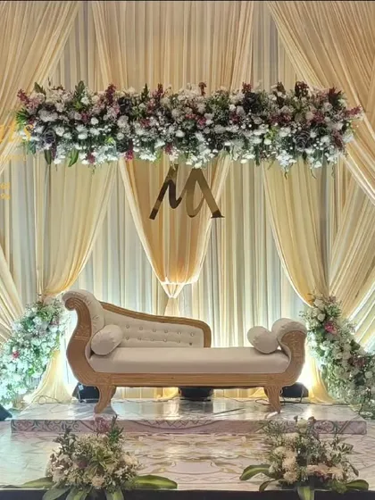 A closer look at one of our engagement ceremony stages, highlighting the dense floral arrangements and custom gold initials for the couple. We focus on details like these to make your wedding decor feel personal and unique.
