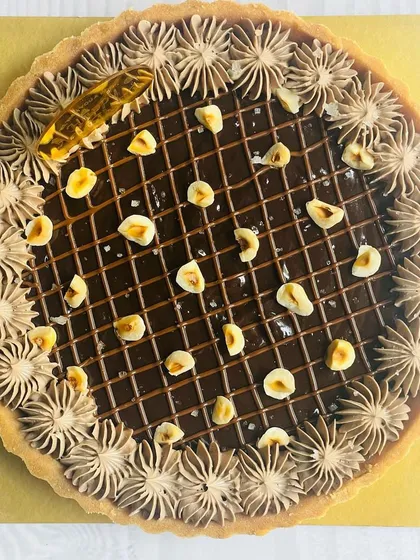 This Nutella Hazelnut tart is pure happiness. It features a creamy Nutella filling, a lattice of chocolate ganache, and is topped with toasted hazelnuts for a delightful crunch.