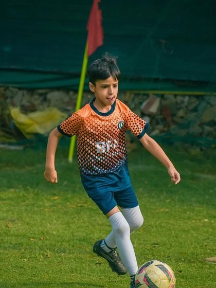 A player dribbles with precision, keeping the ball close while a coach observes his technique from the sideline.