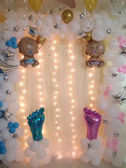 A dreamy, cloud-themed baby shower decoration. I used white balloon clusters to create a cloud effect, accented with a fairy light curtain and foil balloons of babies, a moon, and stars.
