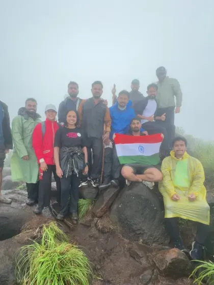 Another group celebrating with the flag on a rocky, rain-drenched peak. The challenging conditions only bring our groups closer together.