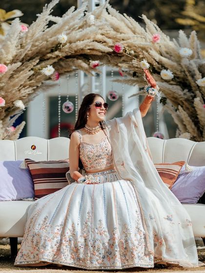 The bride posing with a flower, a happy and graceful shot from her beautiful, sunlit Mehendi ceremony.