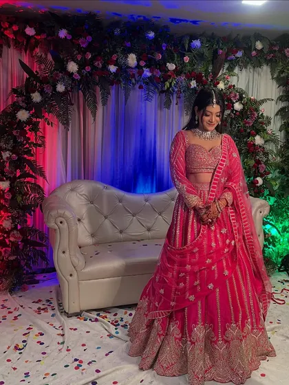 The beautiful bride posing in front of a ring ceremony backdrop I designed. The full floral arch with red and white flowers creates a stunning frame for photos.