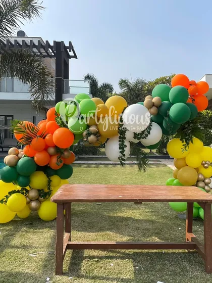 A colorful balloon arch frames an outdoor seating area for a 5th birthday party, blending perfectly with the natural surroundings.
