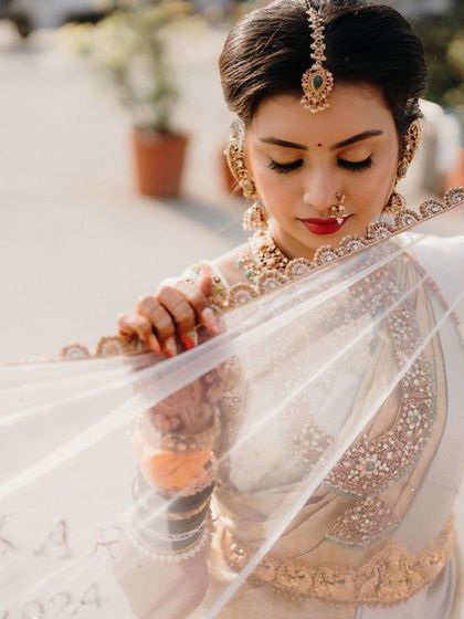 A close-up of the bride looking through her sheer veil. The delicate embroidery on the veil matches the work on her blouse.