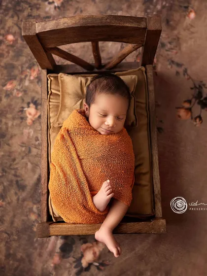 A slightly different angle of the wooden bed pose, showing the baby's peaceful sleeping face and the beautiful textures of the setup.