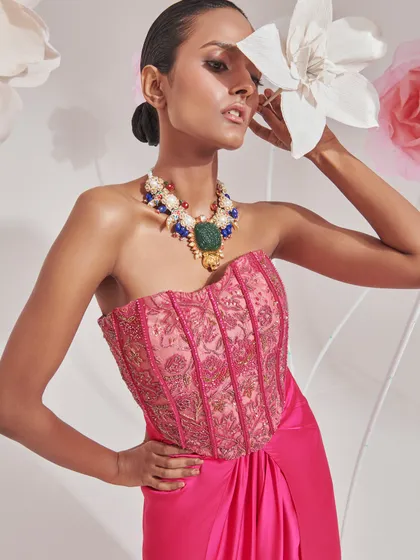A close-up on a fuchsia corset top, paired with a magnificent multi-gemstone necklace. The styling focuses on the intricate embroidery of the top and the bold accessory, creating a look of modern, festive glamour.