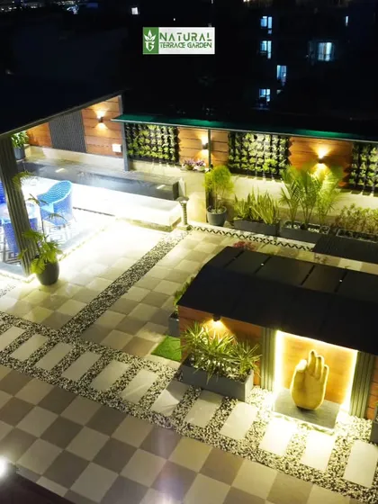 An aerial view of the Palam Vihar terrace at night, showing the layout with the blue-chaired pergola and a separate decorative structure.