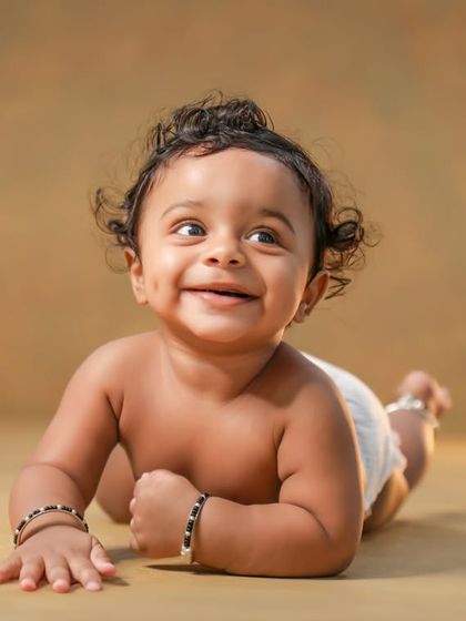 Look at that happy, gummy smile! This little guy is enjoying tummy time during his sitter session. What a joyful moment.