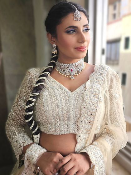 A side profile of the white and silver glam look. This angle highlights the intricate pearl hairstyle and the sharp, defined eye makeup.