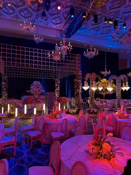A view of the reception layout, where elegant chandeliers and floral arches create intimate zones within a grand space. The mood lighting adds a touch of drama and sophistication. ✨🌸