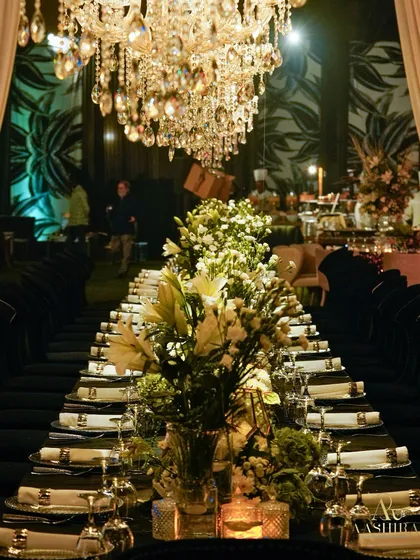 A view down the long banquet table, showcasing the continuous runner of white and green florals under the magnificent crystal chandeliers.