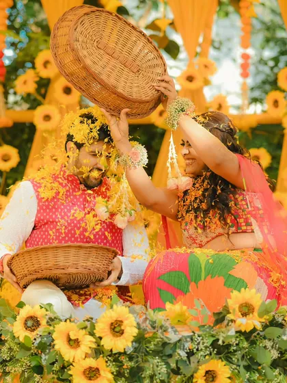 The Haldi ceremony is all about fun. We love capturing moments like this, where the bride playfully showers the groom with flower petals.