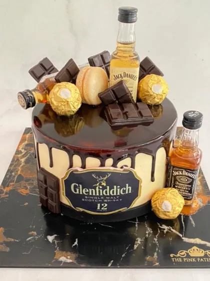 A decadent chocolate drip cake for a whiskey lover. This design is loaded with Ferrero Rocher chocolates, chocolate bars, and miniature bottles of Glenfiddich and Jack Daniel's.