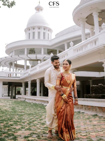 A happy couple posing in front of a grand, white venue. This shot captures both their joy and the magnificent scale of their wedding location.