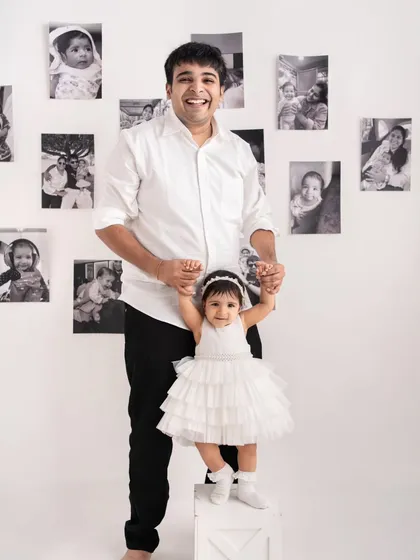 Helping with those first big steps! A proud father supports his daughter as she stands, a precious milestone captured during her first birthday photoshoot.