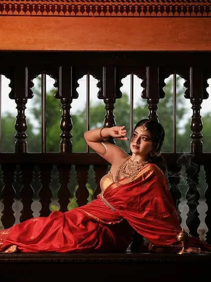 A dramatic pose on a carved wooden bench, this shot plays with shadows and light to create a powerful silhouette. The bride's expression and posture convey a sense of strength and elegance.