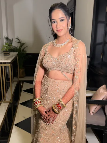 The full view of this elegant reception style. The soft makeup and chic updo allow the intricate details of her mermaid-style lehenga to shine.