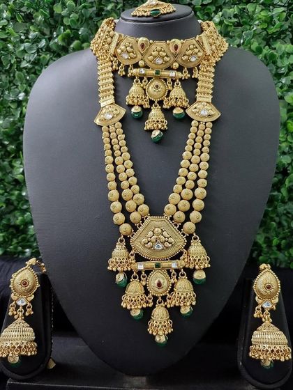 A stunning gold-finish temple jewellery set with multiple cascading jhumkas and intricate carvings, perfect for a grand bridal entry.