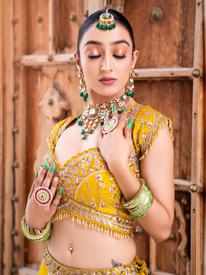 Our American Diamond jewellery is perfect for your sangeet or reception. This bride is wearing one of our modern choker sets featuring high-quality AD work with striking green stones, paired with matching earrings, maang tikka, and statement rings.
