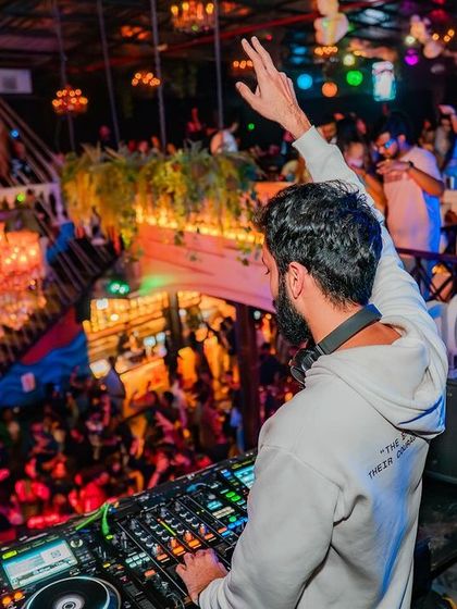 The view from behind, with one hand up, conducting the energy of the dance floor.