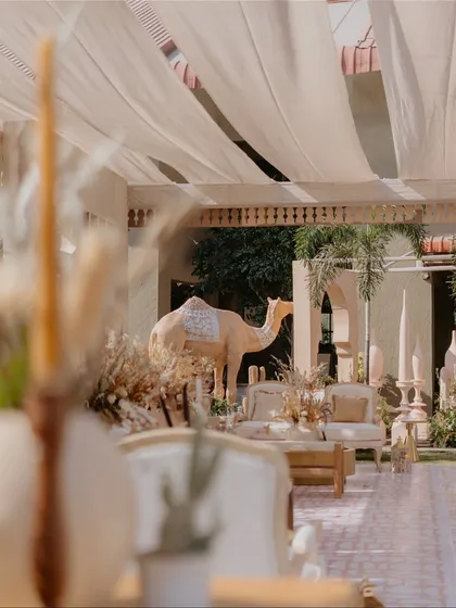 A view of the lounge area, showing how the camel props, fabric-draped ceiling, and neutral-toned furniture work together to create a cohesive and luxurious desert-themed environment.