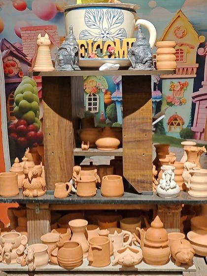 Our display of unpainted terracotta pottery, ready for you to choose from, set against a whimsical, colourful mural.