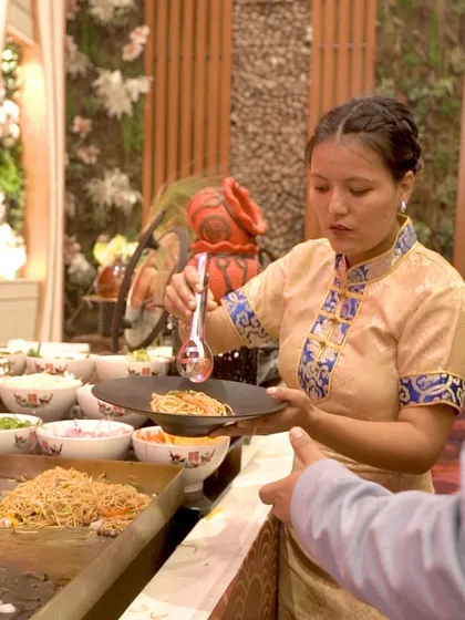 A guest is served a plate of freshly tossed noodles at our live Asian station, showcasing the interactive and personalized service we provide.