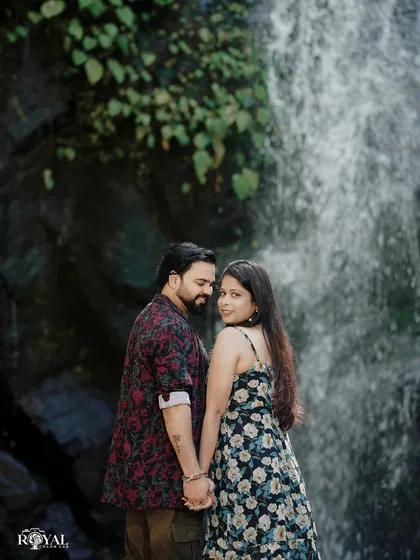 A beautiful portrait of a couple holding hands in front of a waterfall, with the bride looking back at the camera.