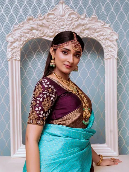 A model in a stunning turquoise and purple saree, wearing a full temple jewellery set.