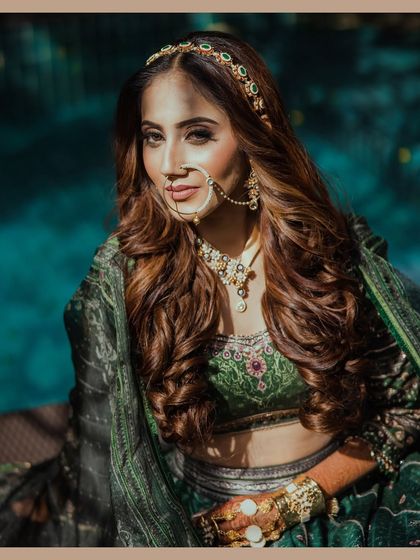 A stunning bridal portrait taken by the pool at The Ananta Udaipur. The bright sunlight and deep shadows create a dramatic, high-contrast look that highlights her beautiful green lehenga.