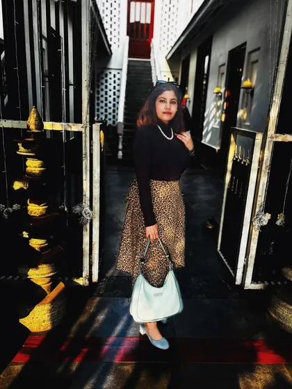 A chic autumn look featuring a black turtleneck and a leopard print skirt, accessorized with a pearl necklace and a light blue bag.