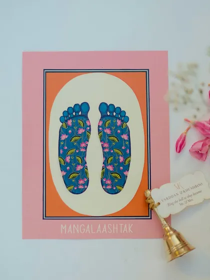 A custom-designed "Mangal Aashtak" card with artistic feet motifs, paired with a small bell, showcasing our attention to personalized and meaningful details.