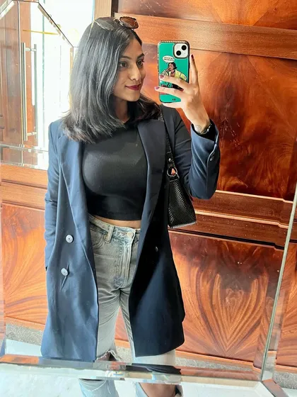 A mirror selfie capturing the full outfit. The navy blazer paired with a black top and bag creates a cohesive and polished look, perfect for a day of meetings.
